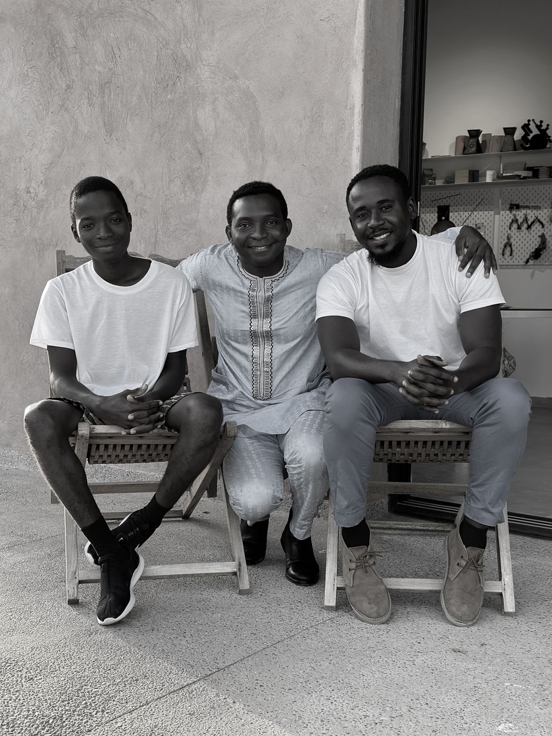 Black and white portrait of three men seated outside the studio
