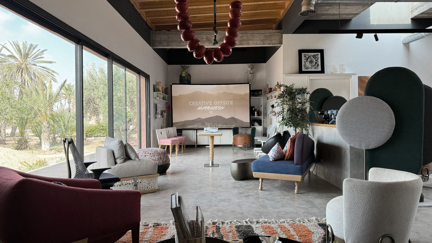 The studio's lounge and presentation room, with a projection screen, glass walls and palms outside